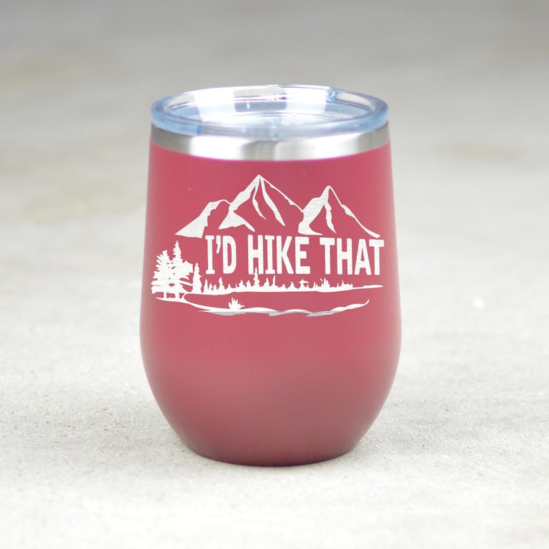 May include: A burgundy stainless steel tumbler with a white mountain range and the text "I'd Hike That".