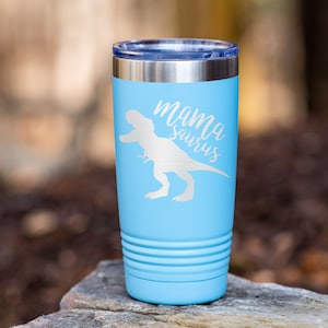 May include: A light blue stainless steel tumbler with a white silhouette of a Tyrannosaurus Rex and the text "mama saurus" on the front.