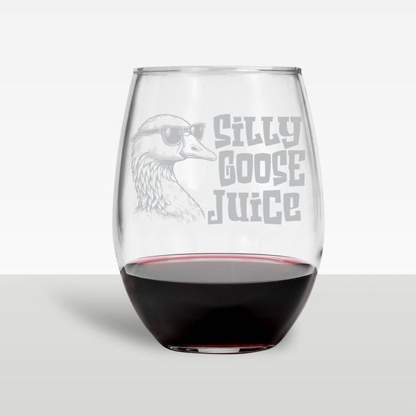 May include: A stemless wine glass filled with red wine. The glass features a design of a goose wearing sunglasses, with the words "Silly Goose Juice" in a playful font. The glass is clear, and the wine is a deep red color.