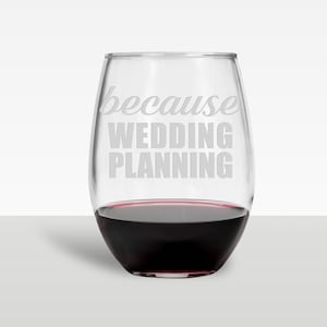 May include: A clear glass stemless wine glass with the text "because wedding planning" etched on the side. The glass is filled with red wine.