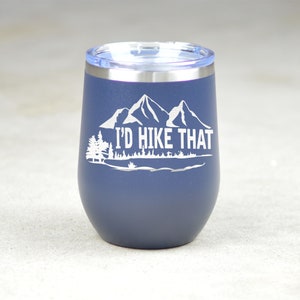 May include: A navy blue stainless steel tumbler with a white mountain range and the text "I'd Hike That".