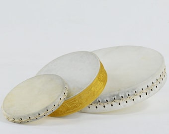 May include: Three white frame drums of varying sizes. The largest drum has a diameter of approximately 18 inches, the middle drum is about 12 inches, and the smallest is around 6 inches. The middle drum features a gold band.