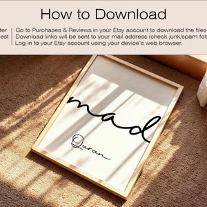 May include: A framed print with the word "mad" in a flowing script and the word "Quran" below it. The frame is light-colored wood, and the background is white. The print is on a brown carpet.