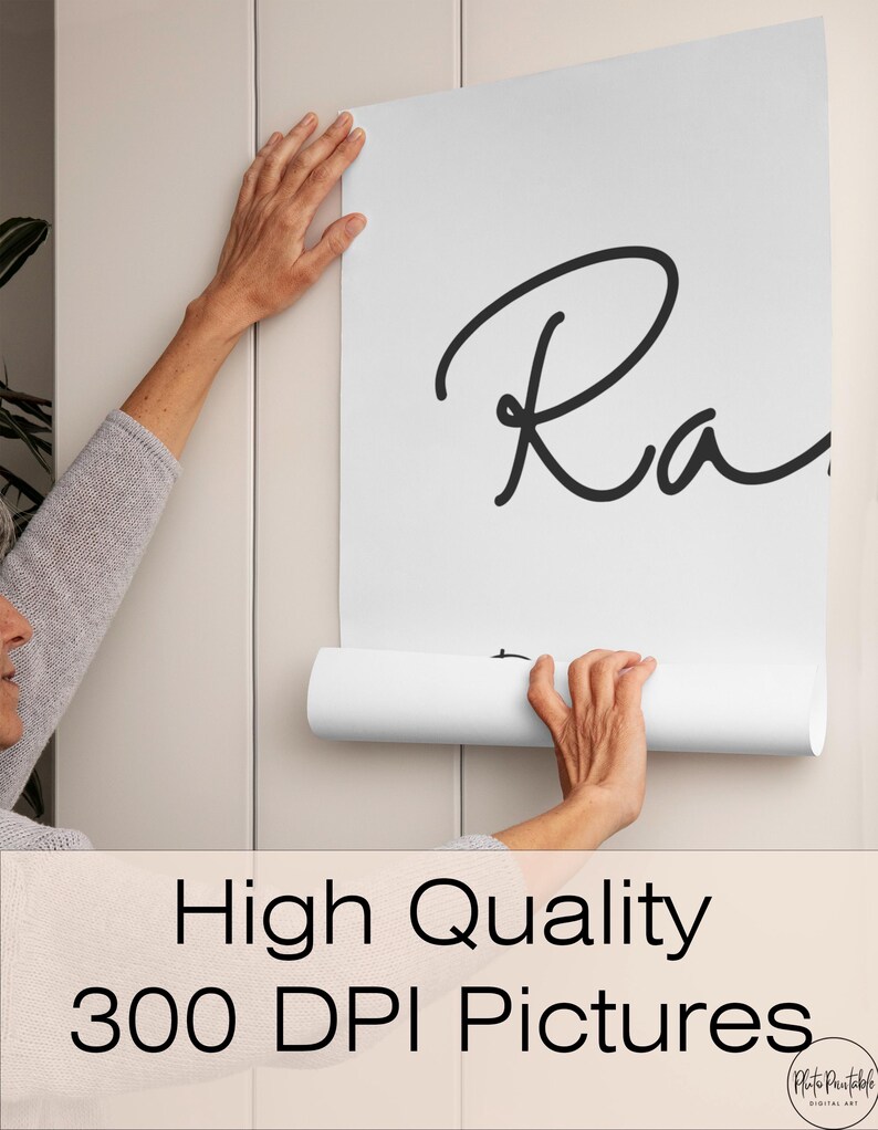 May include: A white poster with the word "Ra" in black script is being held up against a light beige wall. The poster is unrolled, revealing the text. The bottom of the image has the text "High Quality 300 DPI Pictures".