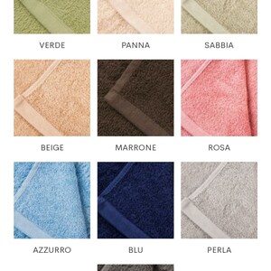 May include: A selection of nine different coloured bath towels. Colours include green, cream, tan, beige, brown, pink, light blue, navy blue, grey, and a darker grey. Each towel has a contrasting border.