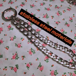 Puede incluir: Un collar de cadena plateado con un colgante redondo abierto de gran tama&ntilde;o. La cadena es de acero inoxidable y tiene un dise&ntilde;o de eslab&oacute;n de curb. El colgante est&aacute; unido a la cadena con un peque&ntilde;o anillo plateado.
