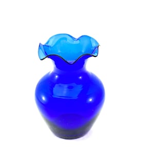 May include: A vibrant cobalt blue glass vase with a ruffled rim. The vase has a rounded body and a darker base, creating a gradient effect. The ruffled rim adds a decorative touch to this elegant piece.