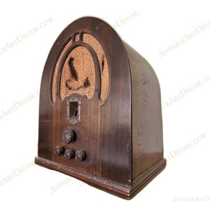 May include: A vintage wooden radio with a brown finish and a cloth speaker grille. The radio has a single knob and three smaller knobs on the front.