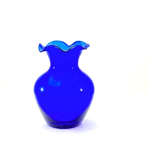 May include: A vibrant cobalt blue glass vase with a ruffled rim. The vase has a rounded body and a slender neck, creating an elegant silhouette. The glossy finish reflects light, highlighting the rich color. A decorative piece for home decor.