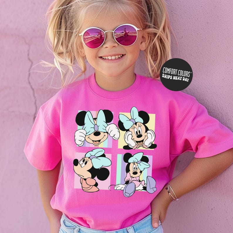 A young girl wearing a pink t-shirt with Minnie Mouse illustrations and sunglasses, smiling at the camera.
