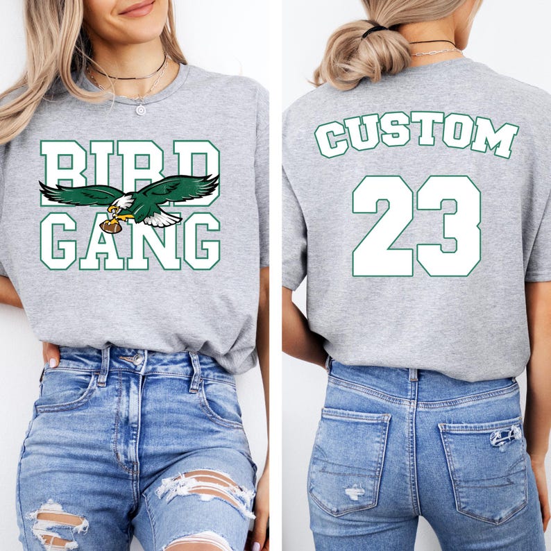 A woman wearing a grey t-shirt with the text "BIRD GANG" and the number "23" printed on it, along with a graphic of an eagle holding a football.