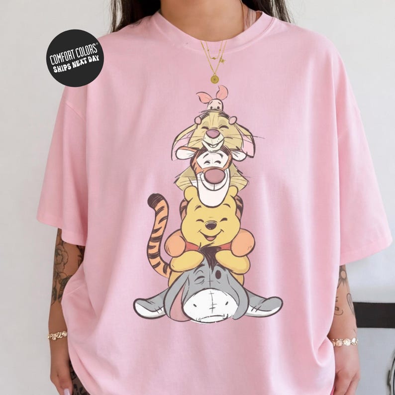 A person wearing a pink t-shirt with a cartoon image of Winnie the Pooh and Tigger.