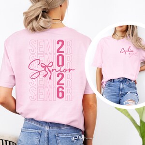 A woman wearing a pink t-shirt with the text "SENIOR 2016" printed on it, along with a ribbon design.