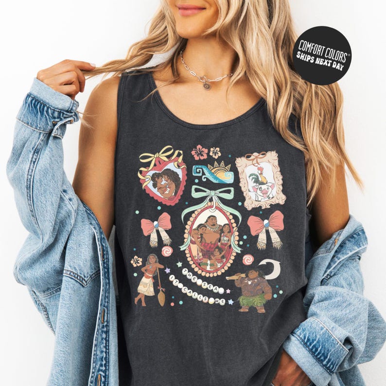 A woman wearing a black tank top with a colorful graphic design featuring various characters and elements, such as a crown, flowers, and a bird.