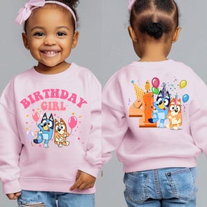a little girl wearing a pink birthday sweatshirt