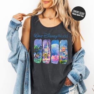 A woman wearing a black tank top with a graphic of Disney World buildings and a denim jacket.