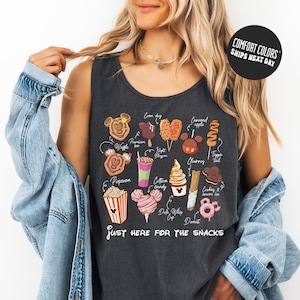 A woman wearing a tank top with a graphic of various Disney-themed snacks and the text "Just here for the snacks" printed on it.