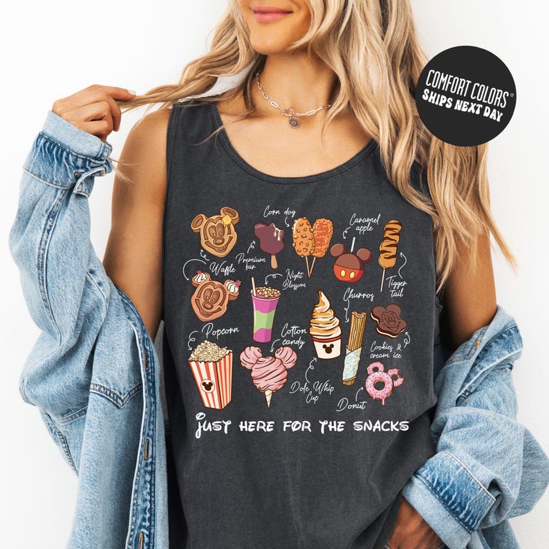 A woman wearing a tank top with a graphic of various Disney-themed snacks and the text "Just here for the snacks" printed on it.