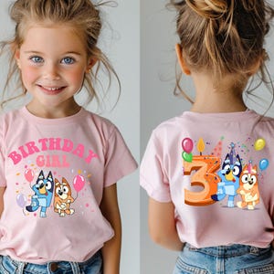 A young girl wearing a pink t-shirt with a cartoon character and the text "BIRTHDAY GIRL" printed on it.