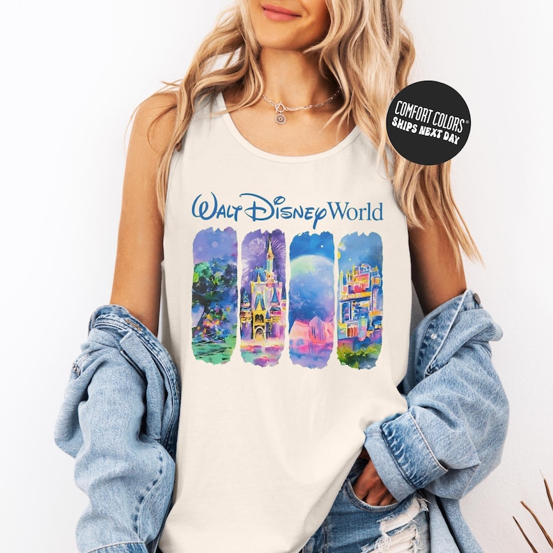 A woman wearing a white tank top with a Disney World graphic and a denim jacket, smiling at the camera.