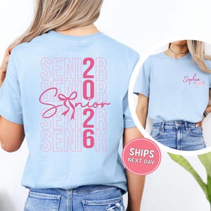 A woman wearing a light blue t-shirt with the text "SENIOR 2016" printed on it, along with a pink ribbon symbol.