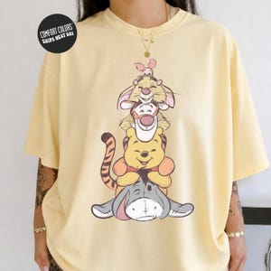 A yellow t-shirt with a cartoon image of Winnie the Pooh and Tigger, along with a heart symbol.