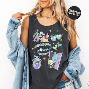 A woman wearing a black tank top with a colorful graphic design featuring cartoon characters and text.