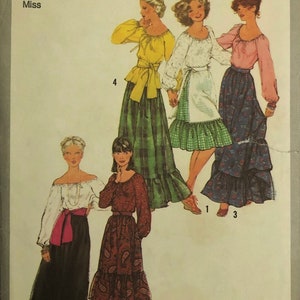 May include: A vintage Simplicity sewing pattern for a women's blouse and skirt. The pattern number is 8244 and the size is 10, with a bust measurement of 83 cm. The pattern shows four different styles of blouses and skirts, all with a peasant-style look.