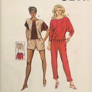Peut inclure: Patron Kwik Sew numéro 1387 pour une tenue en deux pièces. La tenue comprend un haut rouge à manches longues et un pantalon rouge. La deuxième tenue comprend un haut brun et beige à manches courtes et un short beige. Le patron est conçu par Kerstin Martensson.