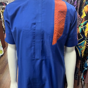 May include: A blue short-sleeved shirt with a long, orange, geometric design on the right side.
