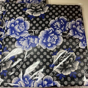 May include: Black fabric with a white and blue floral pattern. The fabric has a repeating pattern of white circles with black centers. The fabric is wrapped in clear plastic and has a white tag with the text "C/F" on it.