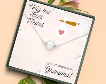 May include: A silver necklace with a large white pearl pendant, presented in a gift box. The box features a stork illustration and the text "Only the Best Moms get promoted to Grandma!" surrounded by pink flowers.