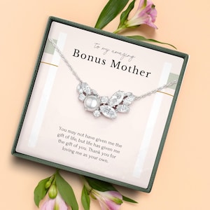 May include: A silver necklace with a pearl and crystal pendant, presented in a gift box with the text "To my amazing Bonus Mother". The box is decorated with pink flowers and a message of appreciation.