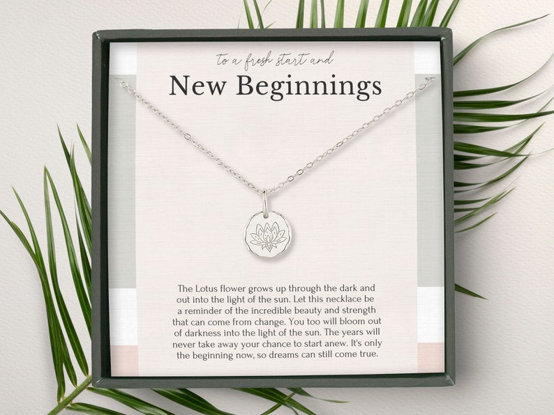 A silver necklace with a round charm in a gift box