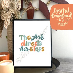 Op de afbeelding: Een printbare digitale download van 8x10 inch met de tekst "The Lord directs her steps" in kleurrijke, handgeschreven letters.