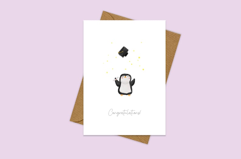 May include: A white card with a black and white penguin wearing a graduation cap. The penguin is surrounded by yellow stars and the text "Congratulations!" is printed below the penguin.