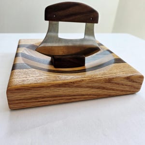 Peut inclure: Une planche &agrave; d&eacute;couper en bois avec un motif incurv&eacute; en incrustation. Un petit couteau incurv&eacute; avec un manche en bois repose sur la planche.