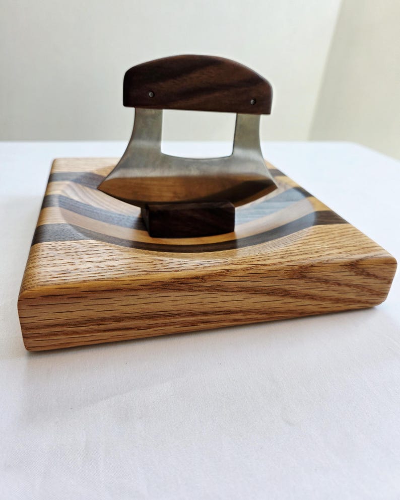 Peut inclure: Une planche &agrave; d&eacute;couper en bois avec un motif incurv&eacute; en incrustation. Un petit couteau incurv&eacute; avec un manche en bois repose sur la planche.