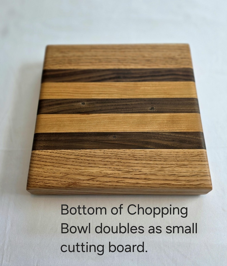 Peut inclure: Une planche &agrave; d&eacute;couper en bois avec un motif ray&eacute; de bois clair et fonc&eacute;. Le dessous de la planche est visible sur l'image. Le texte "Bottom of Chopping Bowl doubles as small cutting board." est imprim&eacute; sous la planche.