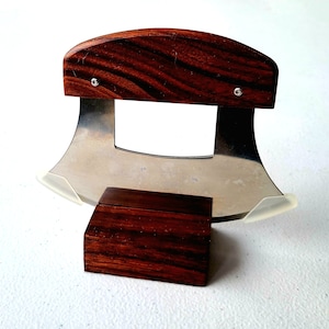 Peut inclure: Un couteau &agrave; lame courbe en acier inoxydable avec un manche en bois et un support en bois. Le couteau a une garde en plastique transparent sur la lame.
