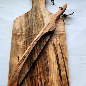 May include: A large, natural Ambrosia Maple cutting board with a unique grain pattern. The board is made by Smoky Mountain Wood Works and has a built-in bread knife.