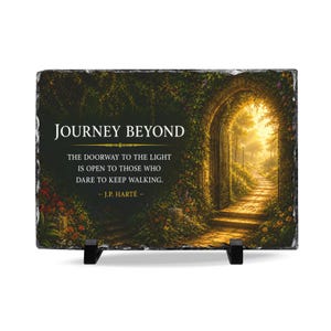 May include: A rectangular slate plaque with rough, chiseled edges, supported by two black stands. The image displays a stone archway leading to a sunlit path, with the text: JOURNEY BEYOND THE DOORWAY TO THE LIGHT IS OPEN TO THOSE WHO DARE TO KEEP WALKING. - J.P. HARTÉ -