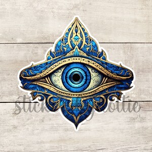 May include: A blue and gold evil eye with intricate floral patterns. The eye is surrounded by a golden frame and has a white pupil.