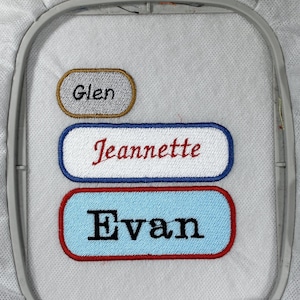 May include: Three embroidered names on a white fabric background. The names are "Glen", "Jeannette", and "Evan".