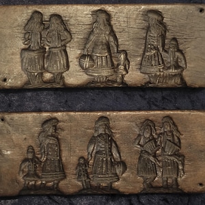 May include: Two antique wooden molds with carved relief figures of people in traditional clothing. The figures are depicted in various poses, some carrying baskets or playing instruments. The wood has a dark, aged appearance.