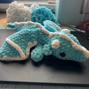 May include: A crocheted blue and white dragon plush toy with a black button eye.