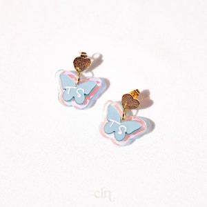 a pair of blue and pink earrings on a white surface