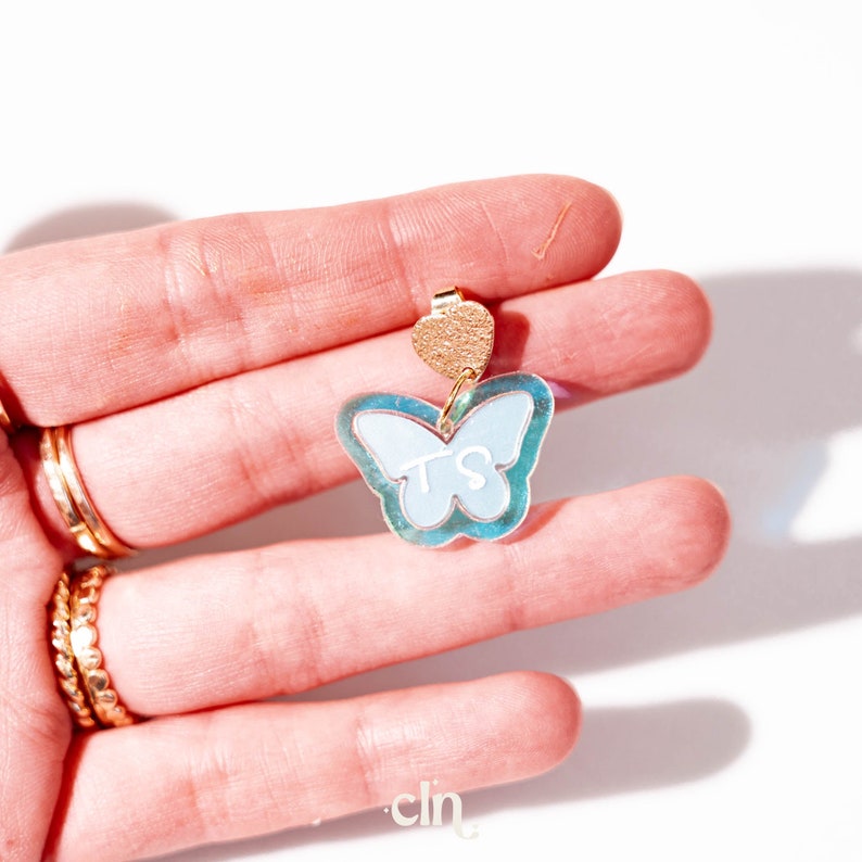 a person's hand holding a blue and white butterfly brooch