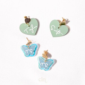 a couple of heart shaped earrings sitting on top of a table