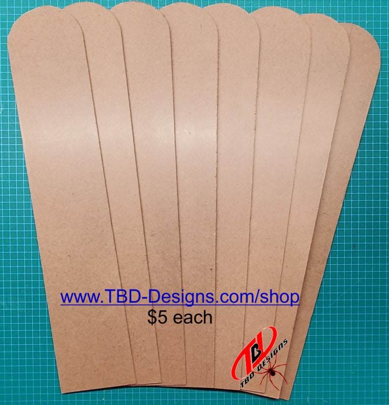 May include: Eight brown leather strips, each with a rounded top and bottom edge. The strips are arranged in a fan shape, with the text "www.TBD-Designs.com/shop" and "$5 each" visible at the bottom.